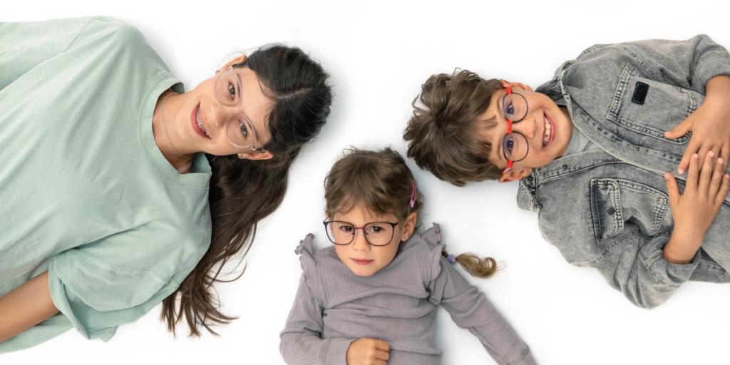 Drie kinderen met een bril op, liggen samen op hun rug en kijken naar de camera